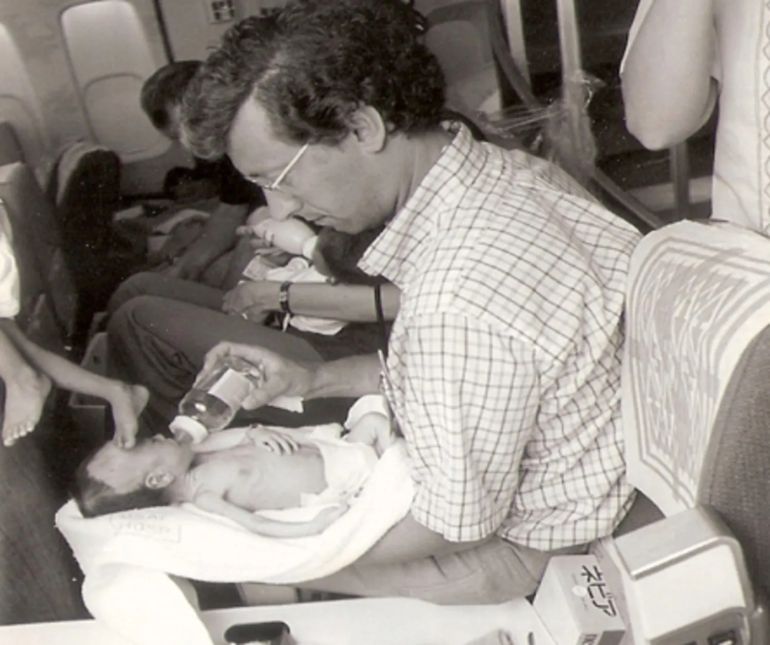 Burkle feeds an infant adoptee on board the plane he accompanied out of Saigon [Courtesy of Frederick Burkle]