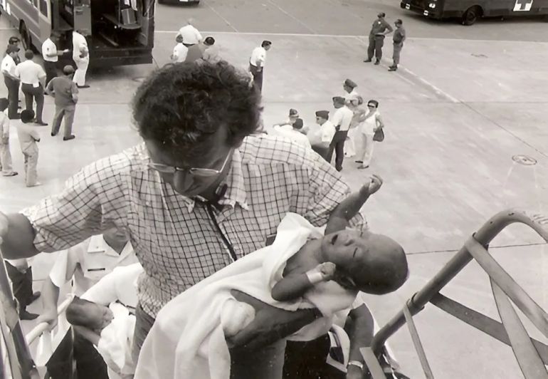 Frederick Burkle carries an infant on board an evacuation plane [Courtesy Frederick Burkle]