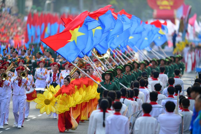 epa12064000 People holding flags march during a parade marking the 50th anniversary of the Liberation of the South and National Reunification Day, in Ho Chi Minh City, Vietnam, 30 April 2025. Vietnamese Reunification Day is observed annually on 30 April. EPA-EFE/STRINGER