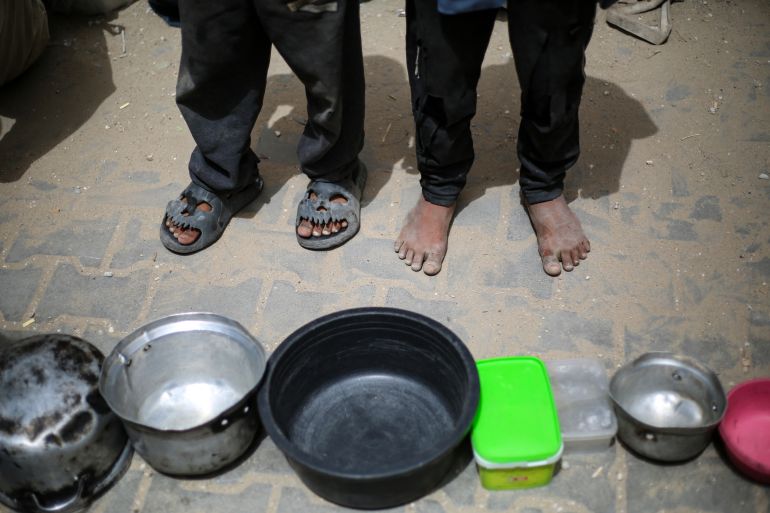 غزة تُعلن رسميا "منطقة مجاعة" جراء الحصار الإسرائيلي 5 TOPSHOT - Palestinian children stand over empty containers at a food distribution centre in the Nuseirat camp for refugees, in the central Gaza Strip, on April 30, 2025.