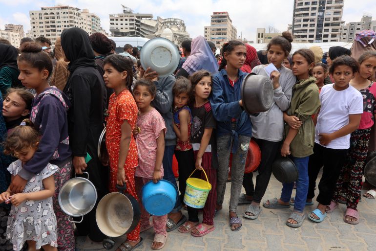 غضب دولي متصاعد من حرب الإبادة والتجويع في غزة 1 TOPSHOT - Palestinians, most of them children, queue in front of a hot meal distribution truck, at a displacement camp near Gaza City's port on May 22, 2025.