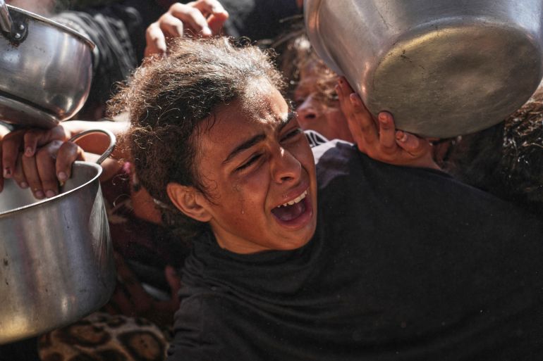 غزة تُعلن رسميا "منطقة مجاعة" جراء الحصار الإسرائيلي 11 A Palestinian girl struggles to obtain donated food at a community kitchen in Khan Younis, in the southern Gaza Strip, Friday, May 9, 2025. (AP Photo/Abdel Kareem Hana)