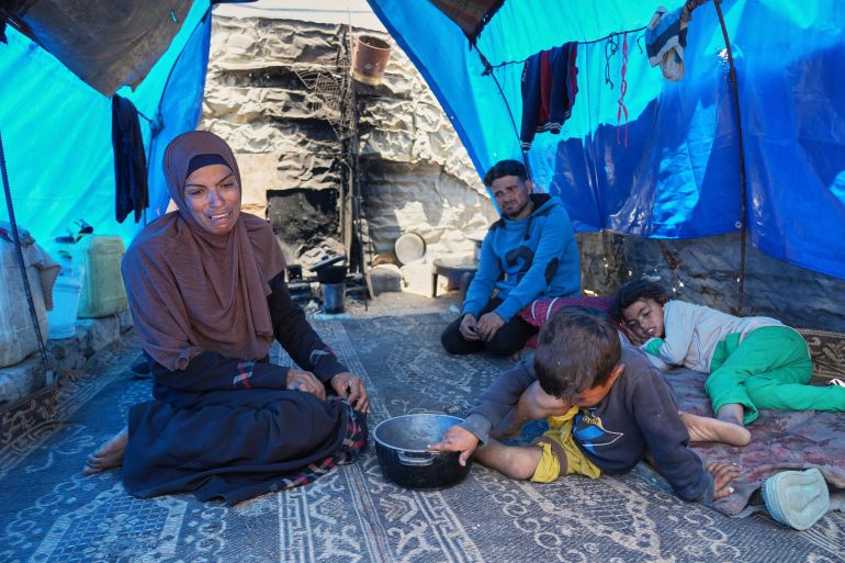 غزة تُعلن رسميا "منطقة مجاعة" جراء الحصار الإسرائيلي 4 Ward Nar, left, reacts as she speaks with the photographer after returning empty-handed from attempting to receive donated food for her family, including her husband Mohammed Zaharna (center right) and their children, Sally (right) and Raed, at a community kitchen in Khan Younis, in the southern Gaza Strip, Friday, May 9, 2025. (AP Photo/Abdel Kareem Hana)