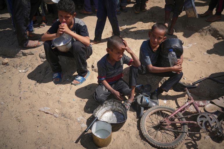 غزة تُعلن رسميا "منطقة مجاعة" جراء الحصار الإسرائيلي 3 Palestinian children wait to get donated food at a community kitchen in Khan Younis, in the southern Gaza Strip, Friday, May 9, 2025. (AP Photo/Abdel Kareem Hana)