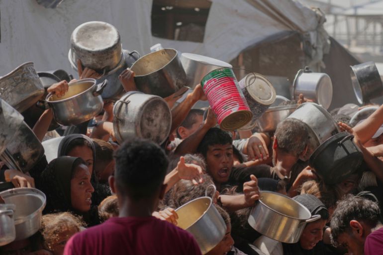غزة تُعلن رسميا "منطقة مجاعة" جراء الحصار الإسرائيلي 2 Palestinians struggle to obtain donated food at a community kitchen in Khan Younis, in the southern Gaza Strip, Friday, May 9, 2025. (AP Photo/Abdel Kareem Hana)