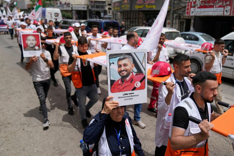 بالصور.. طواقم الهلال الأحمر تطالب بالحماية وسط غياب العدالة في غزة 1 A paramedic holds posters with names and pictures of fellow relief workers who lost their lives in the line of humanitarian duty, during a symbolic funeral for 48 fallen Palestinian Red Crescent Society members during the Israel Hamas war in Gaza, according to a PRCS statement, marking the World Day of Red Cross and Red Crescent, in the West Bank city of Ramallah Monday, May 12, 2025. (AP Photo/Nasser Nasser)
