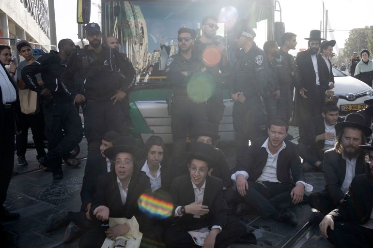 حملة لاعتقال الحريديم الفارين من الخدمة وقادتهم يهددون بإسقاط الحكومة 5 Israeli police stand guard as ultra-Orthodox Jewish men and boys, block a bus from crossing Jaffa Street in central Jerusalem, Thursday, Sept. 29, 2022 to protest attempts to force them to register for Israel's military draft. Military service is mandatory for most Jewish Israeli men, but the ultra-Orthodox often receive exemptions in order to continue their religious studies. (AP Photo/ Maya Alleruzzo)