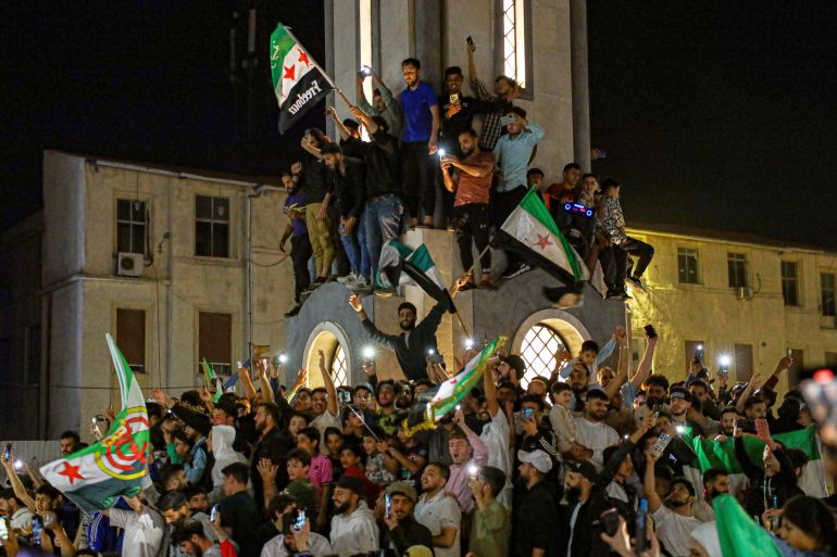 بالصور.. كيف تفاعل السوريون مع قرار رفع العقوبات الأميركية؟ 1 Syrians celebrate after U.S. President Donald Trump announced plans during his visit to Saudi Arabia to ease sanctions on Syria and normalize relations with its new government, in Homs, Syria, late Tuesday, May 13, 2025.(AP Photo/Omar Albam)