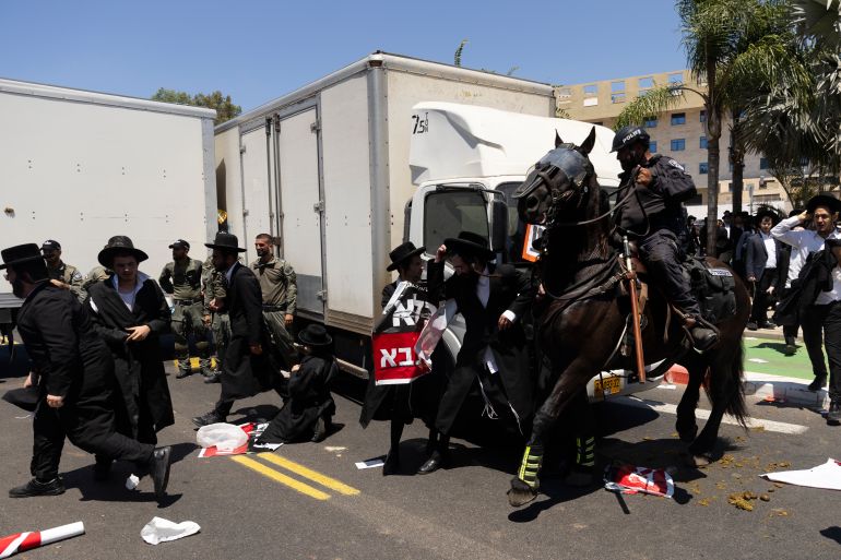 حملة لاعتقال الحريديم الفارين من الخدمة وقادتهم يهددون بإسقاط الحكومة 1 RAMAT GAN, ISRAEL - AUGUST 5: Ultra-Orthodox Jewish men clash with mounted police officers during a demonstration against drafting to the Israeli military near a recruitment base on August 5, 2024 in the Tel HaShomer area of Ramat Gan, Israel. Hundreds of Ultra-Orthodox men who were previously exempted from military service were due to arrive at the recruitment office here today, following a Supreme Court ruling that ended the exemption for yeshiva students. (Photo by Amir Levy/Getty Images)