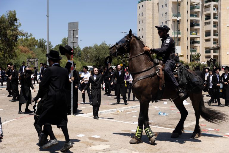 حملة لاعتقال الحريديم الفارين من الخدمة وقادتهم يهددون بإسقاط الحكومة 4 RAMAT GAN, ISRAEL - AUGUST 5: Ultra-Orthodox Jewish men clash with mounted police officers during a demonstration against drafting to the Israeli military near a recruitment base on August 5, 2024 in the Tel HaShomer area of Ramat Gan, Israel. Hundreds of Ultra-Orthodox men who were previously exempted from military service were due to arrive at the recruitment office here today, following a Supreme Court ruling that ended the exemption for yeshiva students. (Photo by Amir Levy/Getty Images)