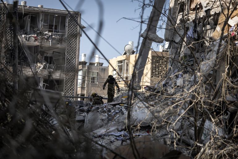 بالصور.. قصف إيران يدمر بات يام وفرق الإنقاذ تبحث عن ناجين 10 Israeli emergency responders search for victims amid the rubble of a damaged building following an overnight Iranian missile strike in Bat Yam on June 15, 2025.